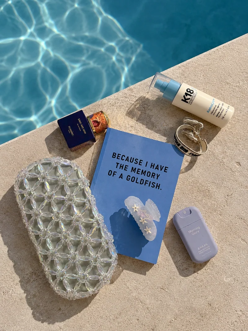The Hair Club claw beside a book and beaded bag by the pool